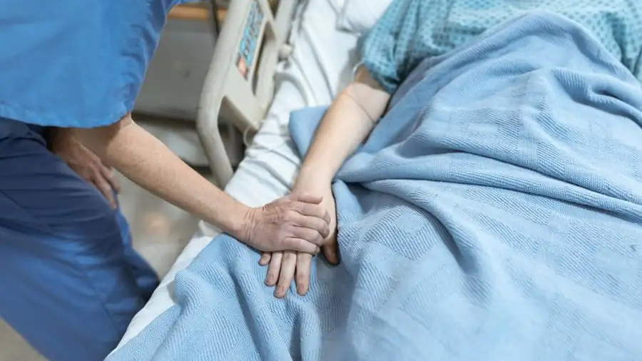 병상에서 환자의 손을 잡아 주는 의료진의 손